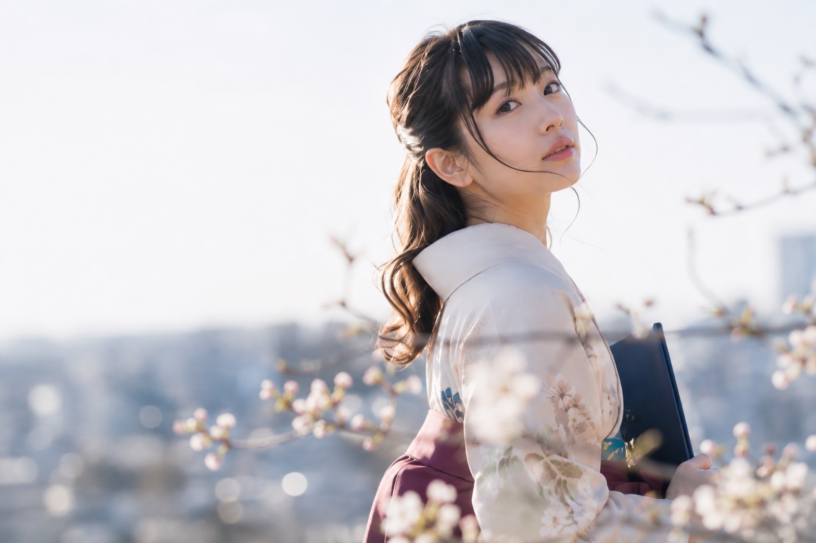 桜を背景に袴姿でふり返る女性のポートレート